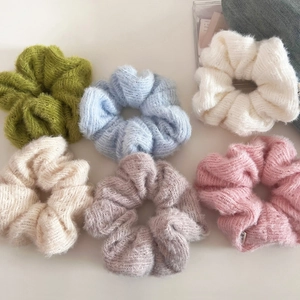 Set of six fuzzy knitted scrunchies in pastel colors on a clean white background