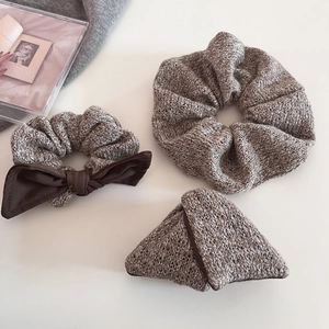Macro view of knit scrunchie set with brown bow and hair clip on beige background
