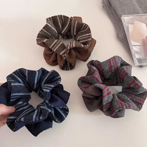 Detailed macro view of three knitted striped scrunchies in brown, navy and grey