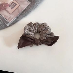 Close-up of knit scrunchie with coffee brown bow on white background and props