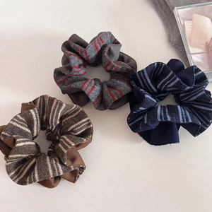 Detailed view of three striped knit scrunchies in brown, grey-red, and blue colors