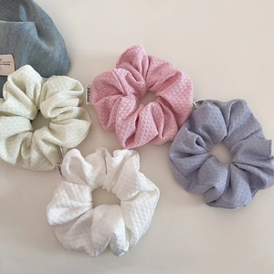 Detailed macro view of pastel waffle knit scrunchies set with branded woven labels