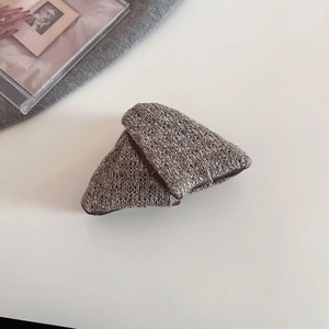 Close-up of textured brown knit hair clips with thick weave texture on a white surface