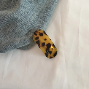Dettaglio del fermaglio per capelli tartarugato con scritta France Handmade su denim