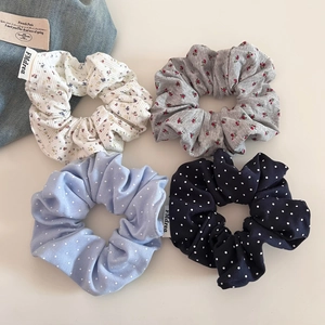 Vue à plat de quatre chouchous en tissu aux motifs floraux et à pois variés