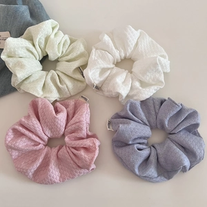 Close-up of four macaron knit scrunchies in mint, white, pink and hazy blue colors
