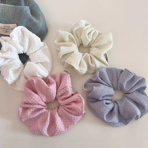 Detail of four textured knit scrunchies in cream white, pink, beige and purple colors