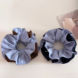 Close-up of two-tone fabric scrunchies in light blue and brown with detailed stitching