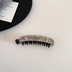 Detailaufnahme einer Haarspange mit Marmortextur und schwarzer Kammbasis
