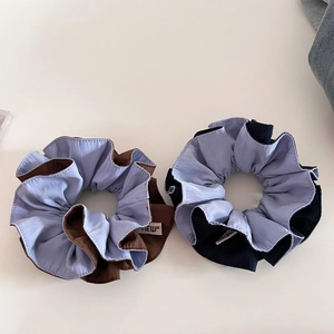Detail of two-tone scrunchies in brown and black with blue contrast and 'NEW' fabric label