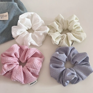 Detail shot of bubble textured cream hair scrunchies in pastel pink purple and yellow