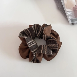 Detailed view of brown striped knitted scrunchie on a white minimalist background