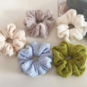Detailed close-up of colorful knitted yarn hair scrunchies in five soft pastel tones