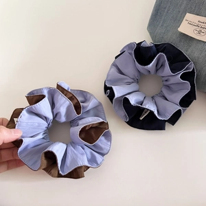 Close-up of two-tone light blue and navy blue fabric scrunchie with pleated texture
