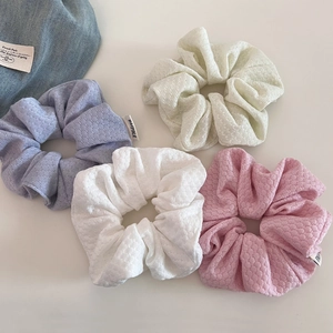 Detailed view of bubble knit texture and woven tags on four-piece hair scrunchie set