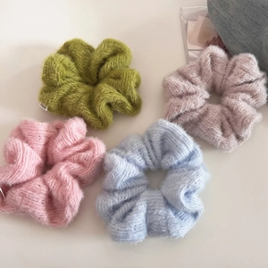 Detailed close-up of colorful knit scrunchies set in green, pink, and blue textured fabric