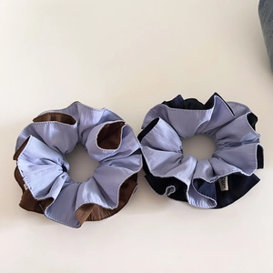 Detail of light blue scrunchies with brown and black contrast piping in soft cotton fabric