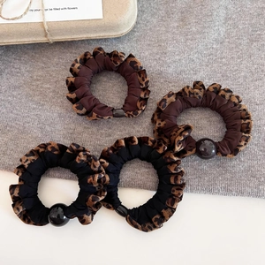 Detail of leopard print hair scrunchies with plush texture and decorative bead embellishment