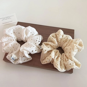 Close-up of hollow lace hair scrunchies in white and beige on a wooden board