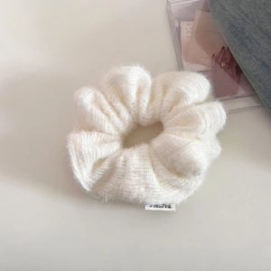Detail of white knitted scrunchie with soft fluffy texture and murea brand label