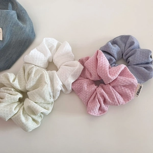 Detailed view of cream bubble knit scrunchies in pastel pink, white, green and blue