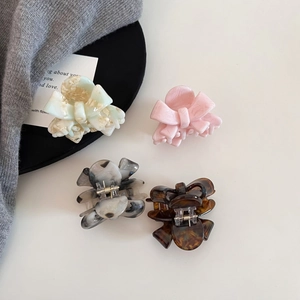 Close-up of acetic acid bow hair clips in marble and pearl textures on a white surface