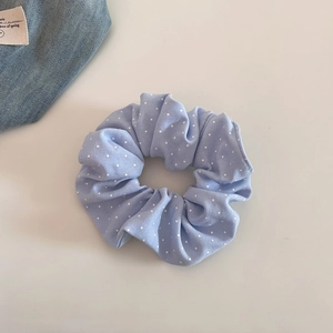Gros plan du chouchou bleu clair à pois blancs avec une texture en coton plissé doux