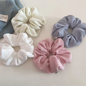 Detailed view of bubble knit texture hair scrunchies in cream, pink and purple pastel tones