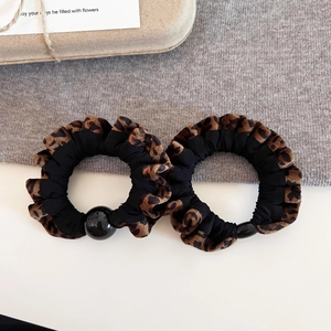 Detail view of two leopard print and black velvet scrunchies with round decorative beads
