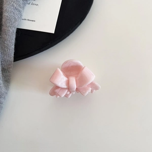 Detailed close-up of pink acetate hair claw with marble texture and bow design