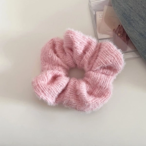 Close-up of pink knitted scrunchie with soft wool texture and elegant pleated design