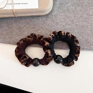 Leopard print scrunchies with black beads for hair styling on minimalist background