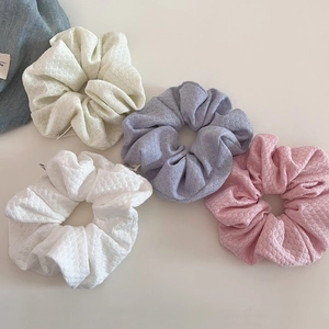 Detailed view of bubble knit scrunchies in cream, lavender, and pink with Finarea labels