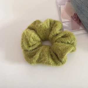 Detailed close-up of a soft grass green knit scrunchie with fluffy faux mink fur texture