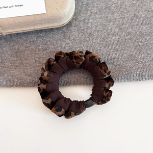Detailed macro view of leopard print scrunchie featuring mixed fabric and plastic buckle