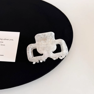 Close-up of a white acetate square hair claw clip featuring a unique woven grid texture