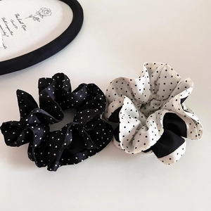 Flat lay of satin polka dot scrunchies in black and white with a decorative plate