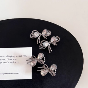 Detail of gunmetal bow hair clips with rhinestones on a black velvet display