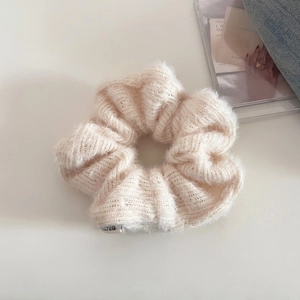 Detailed close-up of a cream knitted scrunchie showing soft mohair texture and label