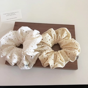 Set of two hollow lace scrunchies in white and beige colors on a wooden tray
