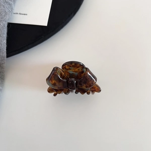 Detail view of a small tortoiseshell acetate bow hair claw clip for elegant styling