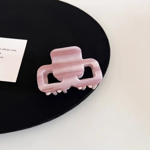 Detail shot of the pink marble textured acetate hair claw clip with hollow square design