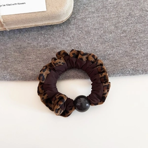 Detail of leopard print plush scrunchie with satin fabric and a black glossy bead