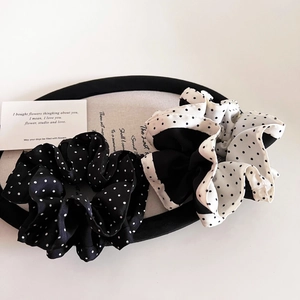 Close-up of two elegant polka dot satin scrunchies in black and white minimalist style