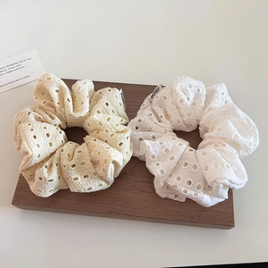 Lace scrunchies in cream and white displayed on a wooden tray for sweet hairstyling