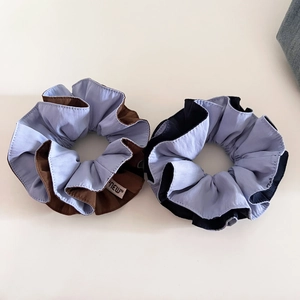 Close-up of two-tone woven fabric scrunchies in light blue and brown with a small NEW tag
