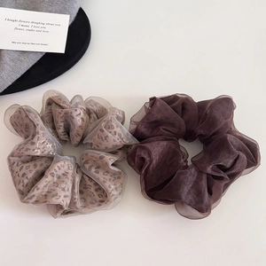 Detail of leopard print and coffee brown organza scrunchies on a white surface