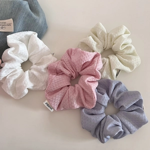 Detailed view of textured bubble knit scrunchies in cream, pink, white and purple