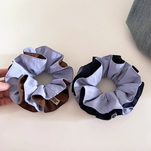 Detail of two-tone large hair scrunchies with pleated texture and stylish new label