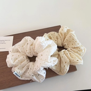 Close-up of white and apricot hollow lace scrunchies with floral embroidery detail